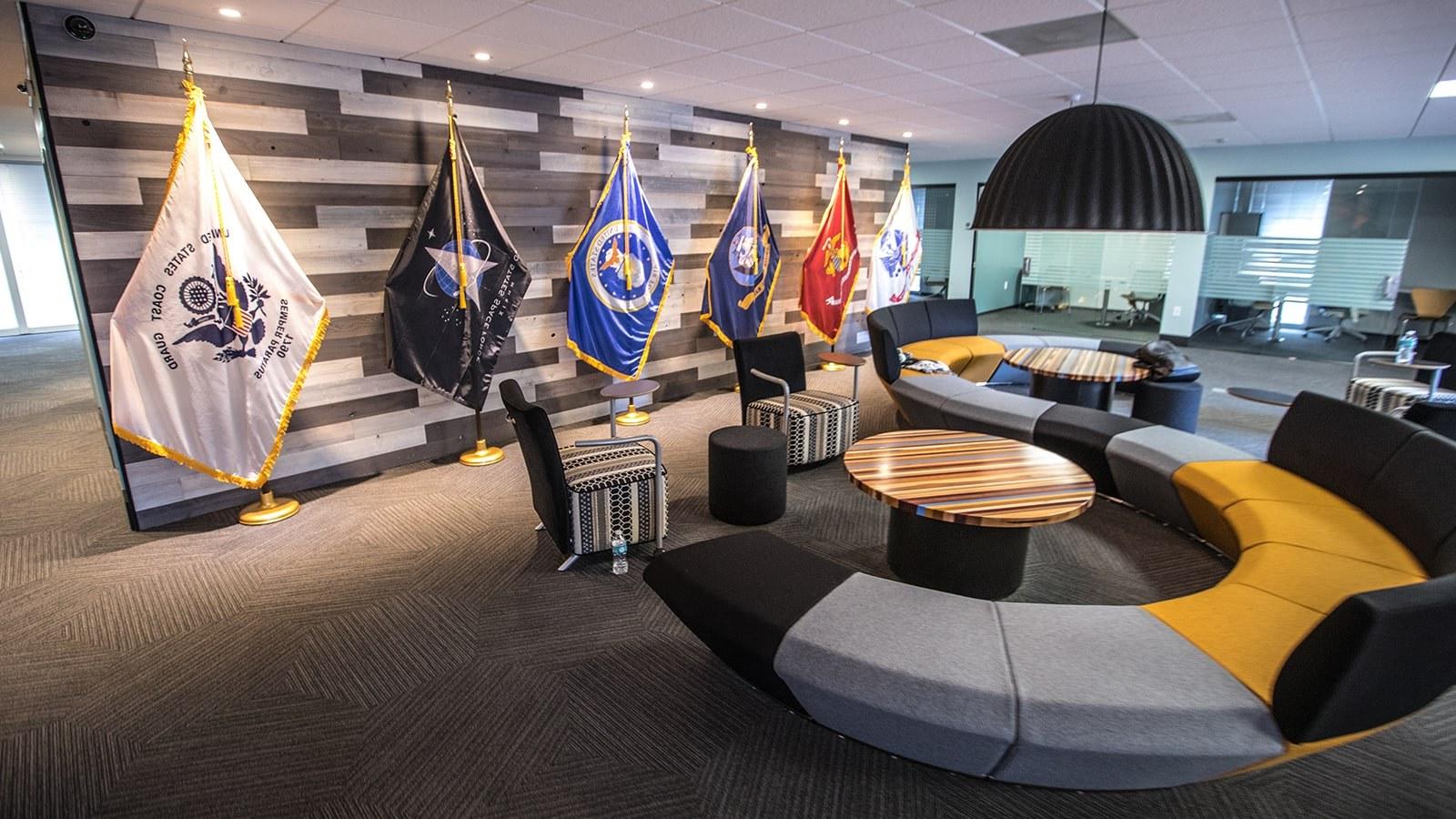 An image of 满帆’s 军事 Student Success center shows a large couch, small meeting rooms, 和 flags representing each branch of the US Armed Services.